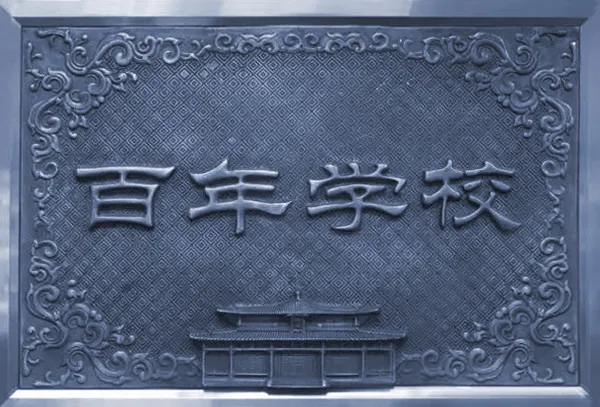 灯市口小学百年学校石雕牌匾实景照片,雕花边框百年学校字样,校园文化环境建设