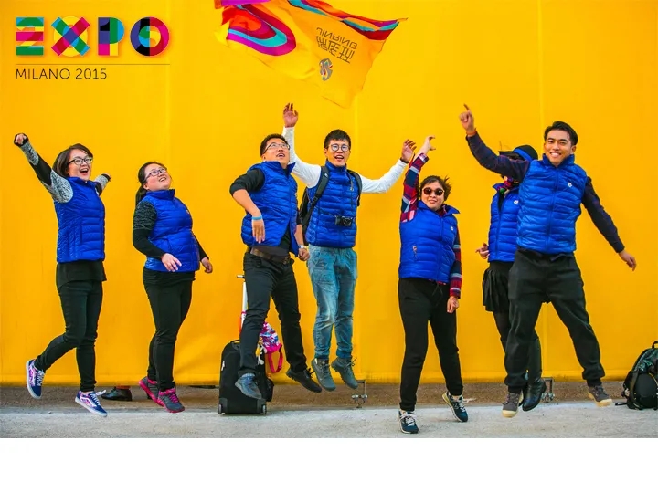 锦连环团队在2015米兰世博会场馆前跳跃合影，身着蓝色队服展现团队风采
