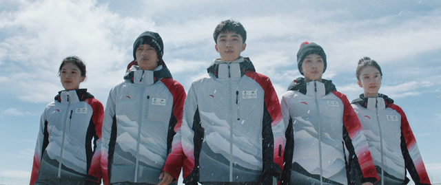 北京冬奥会制服人员雪地合影，多色系服装团队整齐站立展示