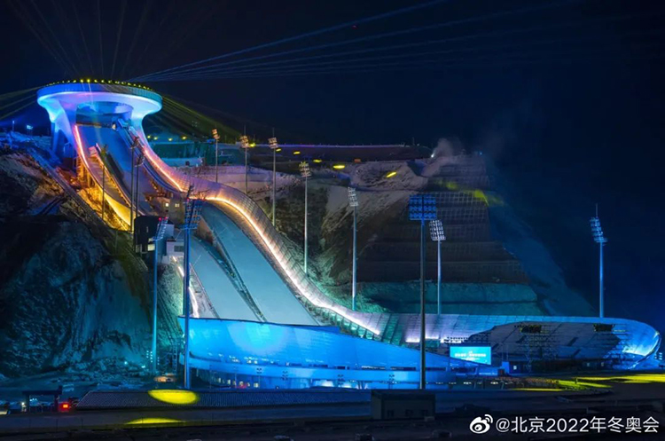首钢滑雪大跳台“雪飞天”夜景，蓝色灯光照亮跳台曲线造型