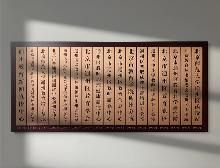 通州区教师研修中心荣誉牌匾墙，多块教育机构木质挂牌排列，体现深厚学术积淀