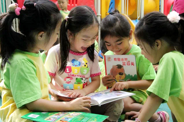 五色土幼儿园孩子们身着绿色园服围坐看绘本实景,锦连环园所文化建设
