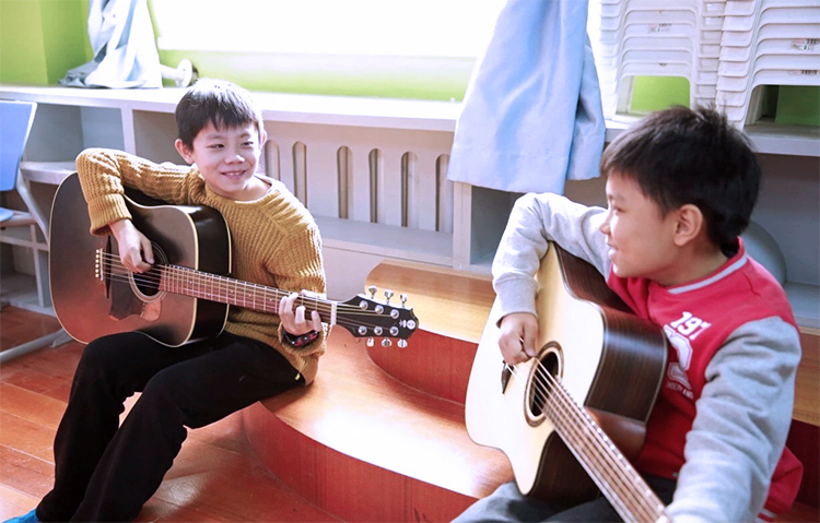 灯市口小学教师与学生弹吉他互动场景,锦连环学校文化建设