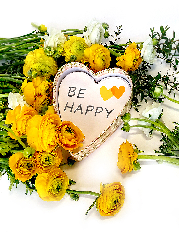 黄色洋牡丹与白色花朵环绕'BE HAPPY'爱心牌的花艺摆设，'一抹金黄'主题暖意配图