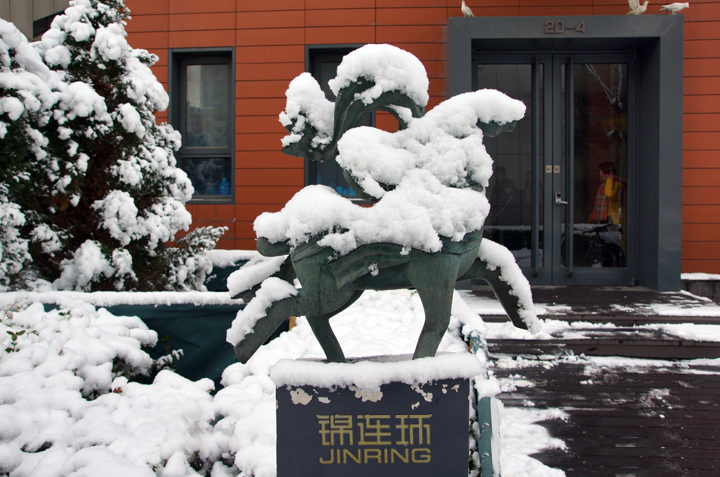 锦连环公司门前覆雪的石狮雕塑，基座印有锦连环JINRING标识的冬日实景