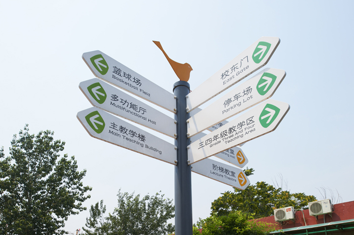 田村中心小学校园户外多向指示牌实景,绿色立柱导视牌指引校园各区域方向