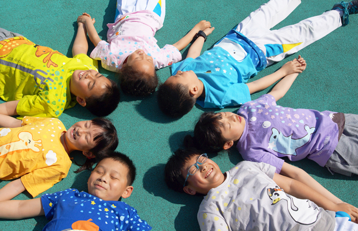 红英小学学生身穿七彩阳光战袍围圈躺地,展现阳光岛校园文化活力氛围