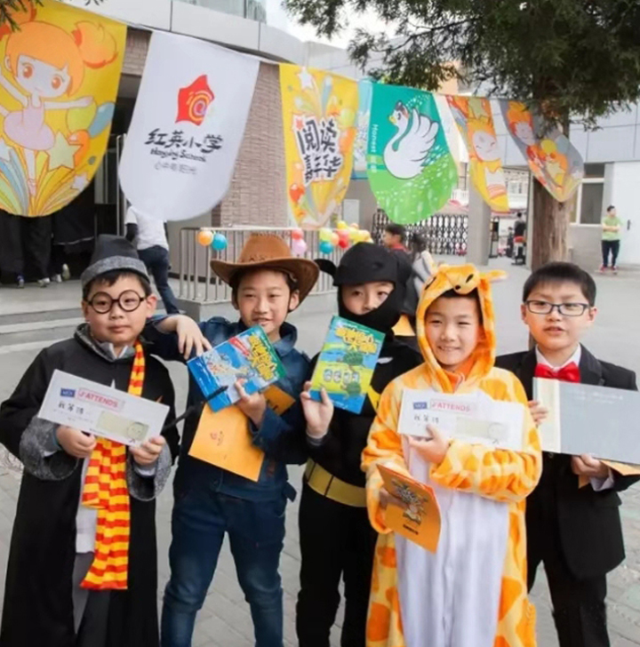 红英小学学生身穿七彩阳光战袍手持品牌物料,校园活动展现阳光岛文化