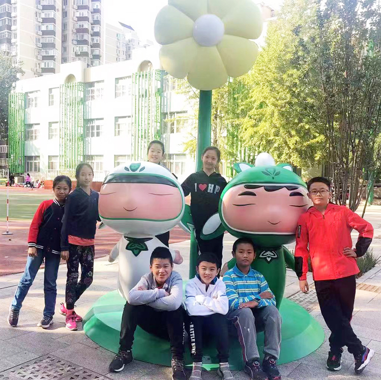 学生在北医附小校园与吉祥物雕塑合影留念，独具特色校园文化建设场景