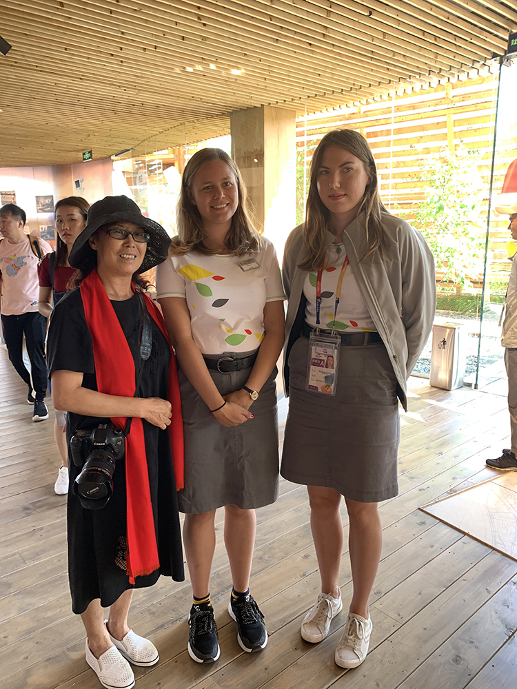世园会内三位身着民族服饰的国际游客留影,脸绘花纹,洋溢节日气氛