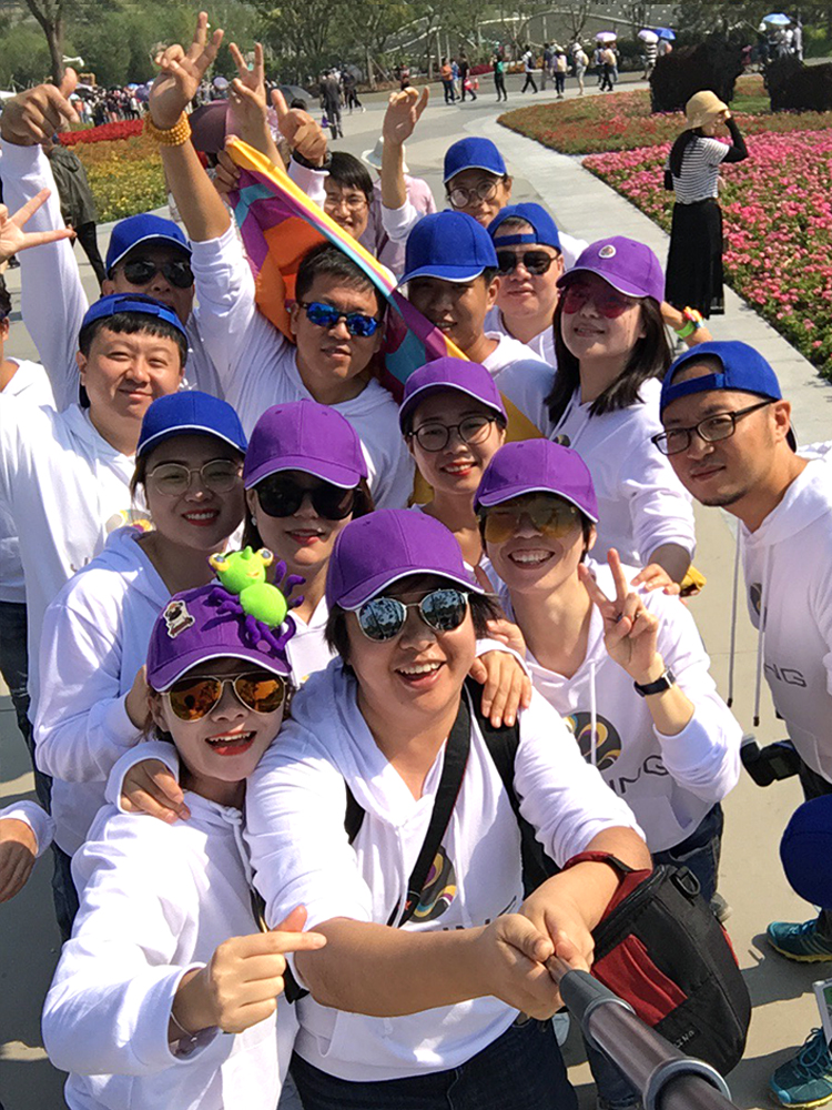 锦连环团队身着白衫头戴紫帽,于世园会花海前欢呼合影,活力四射