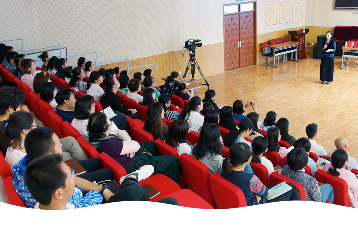 清河第四小学报告厅集会场景，学生坐在红色座椅聆听讲座，讲台上教师授课，展现校园文化活动
