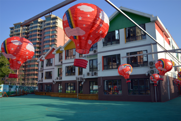 立新幼儿园教学楼外景，楼体悬挂热气球造型红灯笼，展现校园文化环境建设