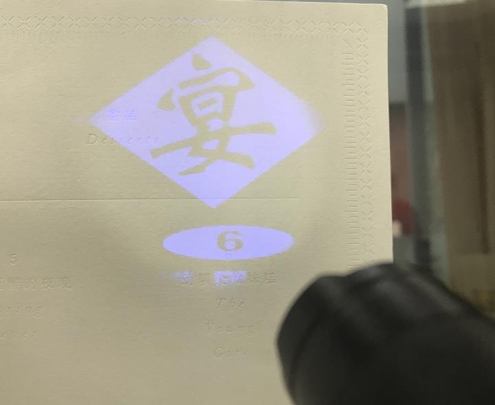 借助小型投影手电将宴字图案投射于笔记本页面，展示勘探系笔记本的趣味互动创意设计