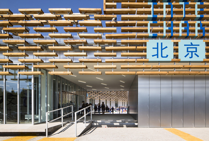 北京法国国际学校木格栅入口大厅内景，挂有北京标识，木质隔栅通透明亮，体现校园导视与文化设计