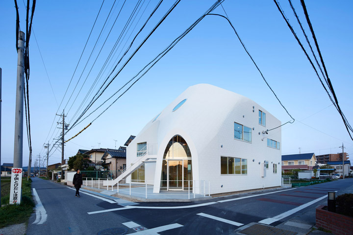 日本四叶草之家幼儿园白色建筑街道实景，造型轻快明亮如帐篷，展现打破传统的幼儿园建筑文化设计