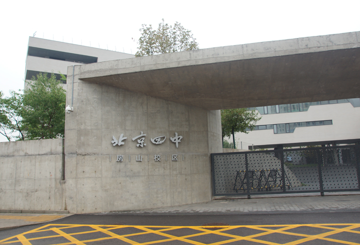 北京四中房山校区清水混凝土入口外景，墙面镌刻北京四中标识，体现学校文化建设简约自然的风格