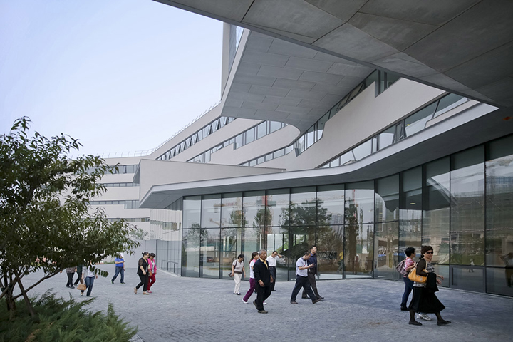 北京四中房山校区清水混凝土曲线建筑与学生活动场景，自然光线通透，展现绿色校园环境建设设计