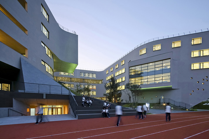 北京四中房山校区教学楼与运动跑道场景，建筑形态自然环保，呈现校园环境建设简约朴素的风貌