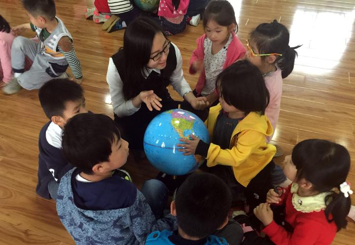 孩子们围着教师手持地球仪学习探索，中科大幼儿园科学启蒙教育活动场景