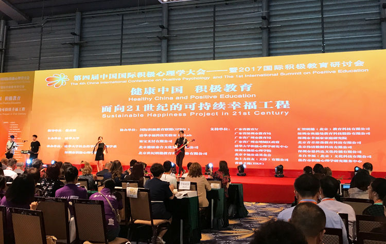 大会舞台与“健康中国 积极教育”红色主题背景，可持续幸福工程论坛现场