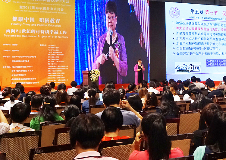 演讲嘉宾在积极心理学大会舞台分享，大屏展示课程章节内容