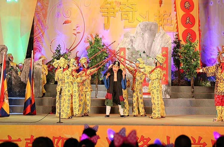 兴隆小学大型戏剧展演舞台，众多学生身着戏服在绚丽灯光中表演，呈现戏润文化教育特色
