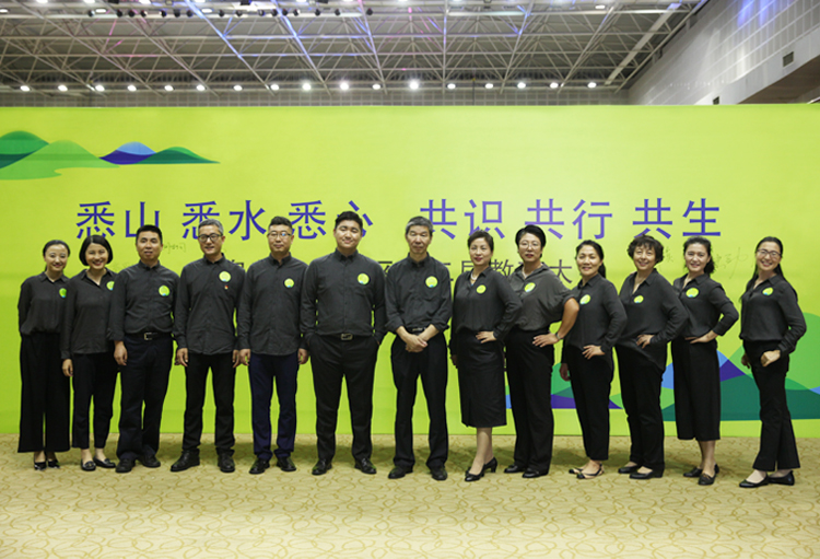 温泉苏家坨教育大会教师身着深色服装登台合影，背景大屏展示大会主题标语