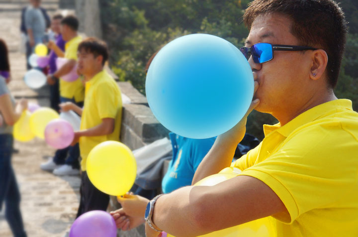 身着黄色队服的锦连环成员在长城上吹气球,趣味互动其乐融融