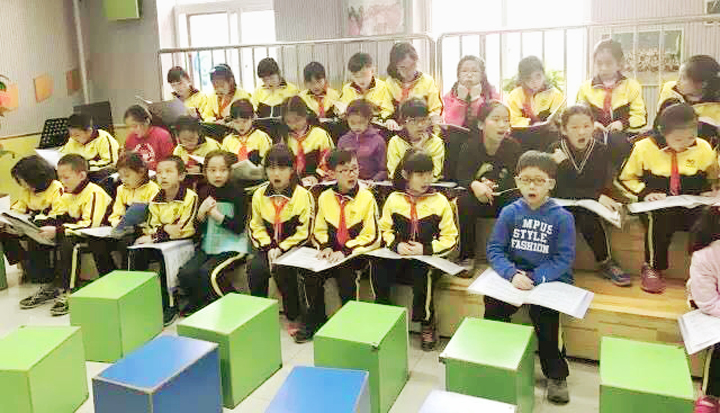 北京石油附小学生身着校服佩戴红领巾在教室齐读书本，校园学习场景
