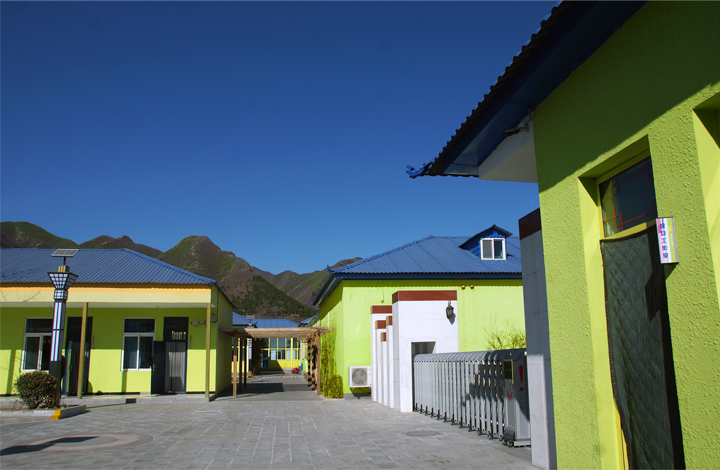 昌平南口山区桃洼学校绿色教学楼与远山蓝天，展现校园环境建设与山区校园自然风貌