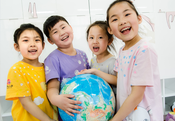 红英小学四名学生笑容灿烂围抱地球仪,展现阳光教育下学生的快乐成长与校园文化氛围