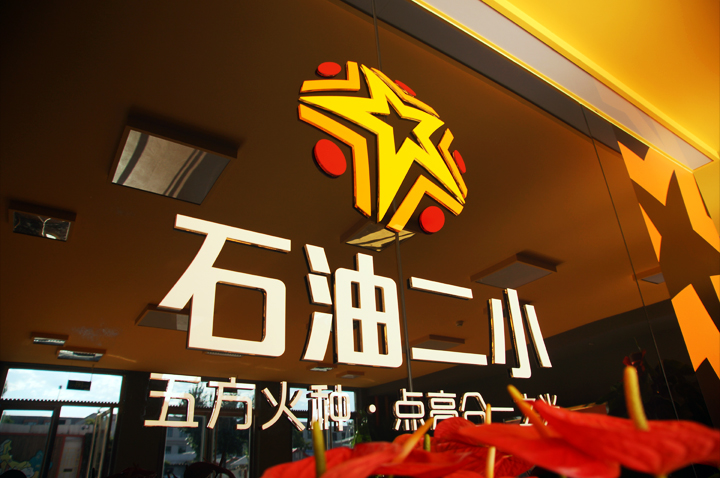 石油二小品牌墙设计，黑底金色星形logo与星火理念语，锦连环教育品牌设计
