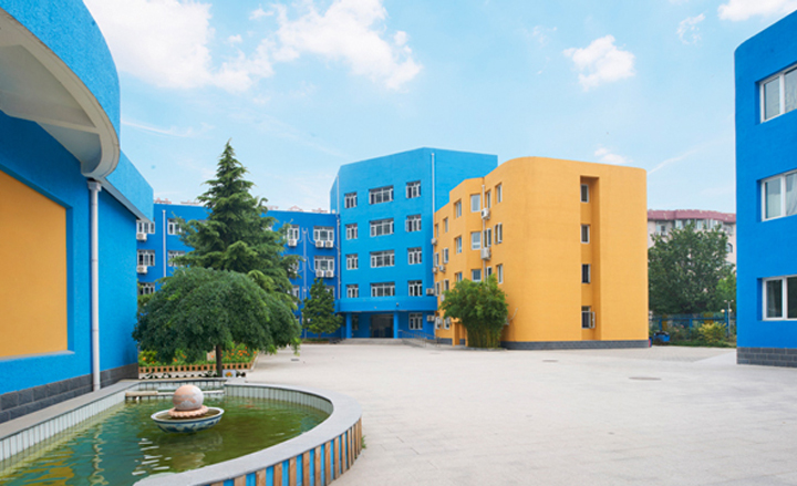 北京丰合第五小学校园实景，蓝橙相间教学楼与中心庭院水池，整体校园环境建设面貌