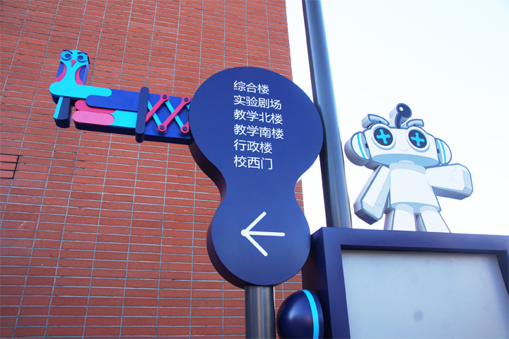 海淀实验二小校园导视系统实景，红墙方向指引牌与吉祥物结合的导视设计